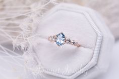 an engagement ring with a blue topaz surrounded by white feathers