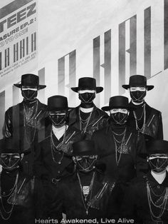 a group of men in black suits and hats standing next to each other with chains on their necks