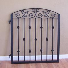 a black iron gate on the floor in front of a beige wall with wood floors