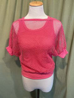 This is a fun vintage top from the 70s or 80s.  Labeled has been snipped out. The bust measures 25" to 34", see measurements below. This fun top has the look of 2 layered tops but is all in one. It is a pink cotton blend strappy, sleeveless tank top bottom layer with a mesh short sleeve top layer. The two layers are attached at the band bottom. The tank part is a soft ribbed tank. The mesh is an open weave with dolman sleeves. The sleeves have knit cuff bands, as does the neckline.    The top is in very good condition!  No damage or soil. Super cute!  If you have never worn vintage before, please measure yourself!! Vintage sizes run smaller than today's sizes, know your measurements before buying! Bust measured from side seam to side seam at the underarm: stretches from 12.5" to 17" for a 90s Style Stretch Tops For Spring, Pink Retro Stretch Top, Pink Stretch Retro Top, Pink 90s Style Spring Tops, Stretch 90s Style Tops For Spring, Pink 90s Style Crop Top For Spring, Stretch 90s Tops For Spring, Stretchy 90s Style Tops For Spring, Retro Stretch Pink Top