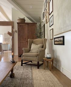 a living room filled with furniture and pictures hanging on the wall next to a wooden table