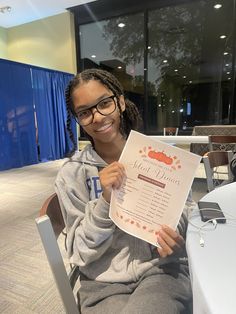 a woman sitting at a table holding up a sign