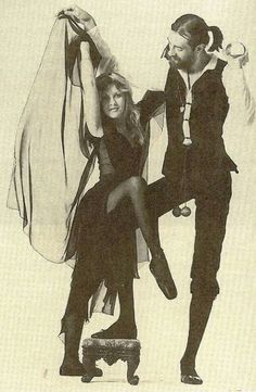 the man and woman are dressed up in black clothes, one is holding on to her leg