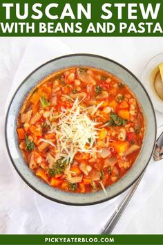 a bowl of vegetable soup with parmesan cheese on top and spoons next to it