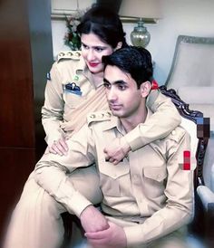 a man in uniform sitting next to a woman on a chair with her arm around him