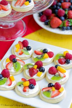 small desserts are arranged on a white platter with fruit and kiwi slices