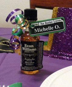 a bottle of alcohol sitting on top of a purple table cloth next to a plate