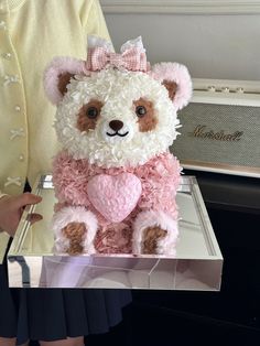 a teddy bear that is sitting in a box with some kind of decoration on it