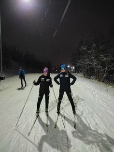 three people on skis in the snow at night