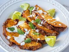 a white plate topped with fried potatoes covered in sour cream and cilantro