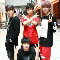 four young men posing for the camera with their hands in the shape of peace signs