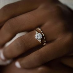 a woman's hand with a diamond ring on her left hand and the other hand holding