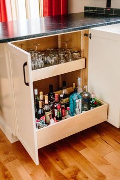 an open cabinet filled with liquor bottles and glasses on top of a hard wood floor