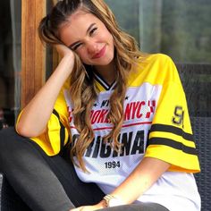 a young woman sitting on top of a couch wearing a yellow and white jersey shirt