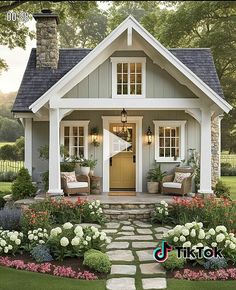 a small white house with flowers around the front door and steps leading up to it