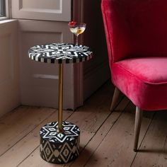 a red chair sitting next to a table with a wine glass on top of it