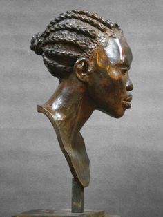 a bronze statue of a woman's head with braids on top of it