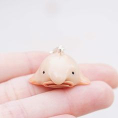 a tiny white bird sitting on top of someone's finger with a ring in it's mouth