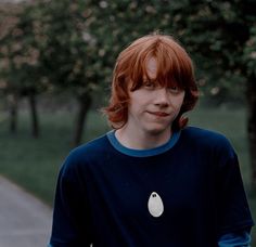 a young man with red hair wearing a blue shirt and holding a white object in his hand