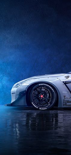 a white sports car parked on top of a wet ground next to a dark blue background