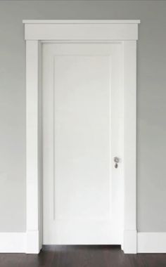 an empty room with a white door and hard wood floor