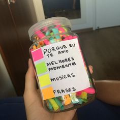 a jar filled with lots of different colored confetti next to a person's hand