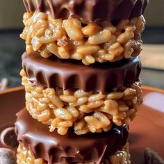 three chocolate covered desserts stacked on top of each other with nuts in the middle