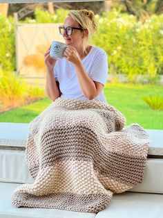 a woman sitting on a window sill drinking coffee