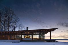 a large building sitting on top of a snow covered ground next to trees and water