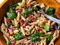 a wooden bowl filled with pasta and vegetables