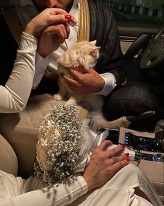 a man and woman sitting in the back seat of a car with a cat on their lap