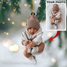 an ornament hanging from a christmas tree with a baby wrapped in a blanket