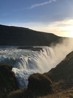 the sun is shining over a large waterfall