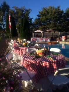 tables and chairs are set up by the pool for an outdoor party or celebration with red gingham cloths on them