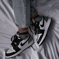 black and white photo of someone's feet wearing nike air jordans on a bed