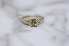 a gold ring with an oval cut green stone in the middle and two small diamonds on each side