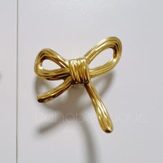 a close up of a gold colored bow tie on a white door with the handle down