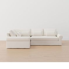 a white couch sitting on top of a hard wood floor next to a white wall