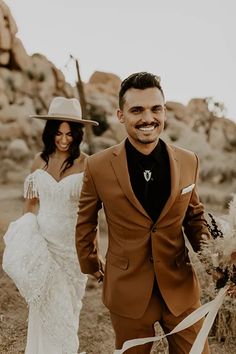 a bride and groom walking through the desert