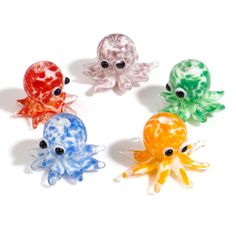 four different colored glass octopus figurines on a white surface