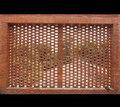 a red brick wall with an intricate lattice design on the top and bottom part, in front of it