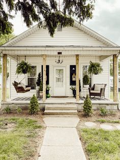 a small white house with porches and chairs