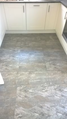 a kitchen with white cabinets and gray flooring