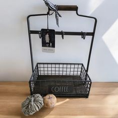 a metal basket with two balls of yarn in front of it and a coffee sign hanging on the wall