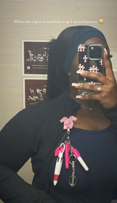 a woman taking a selfie with her cell phone and keychain attached to her neck