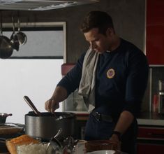 a man standing in front of a pot on top of a stove next to a pan filled with food