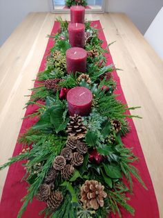 a red table runner with pine cones and candles