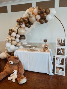 a teddy bear sitting on the floor next to a table with balloons and other decorations