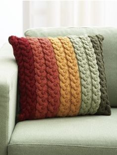 a green couch with multicolored knitted pillows on it's back side