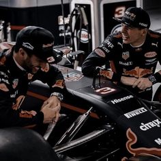 two men sitting on top of a racing car